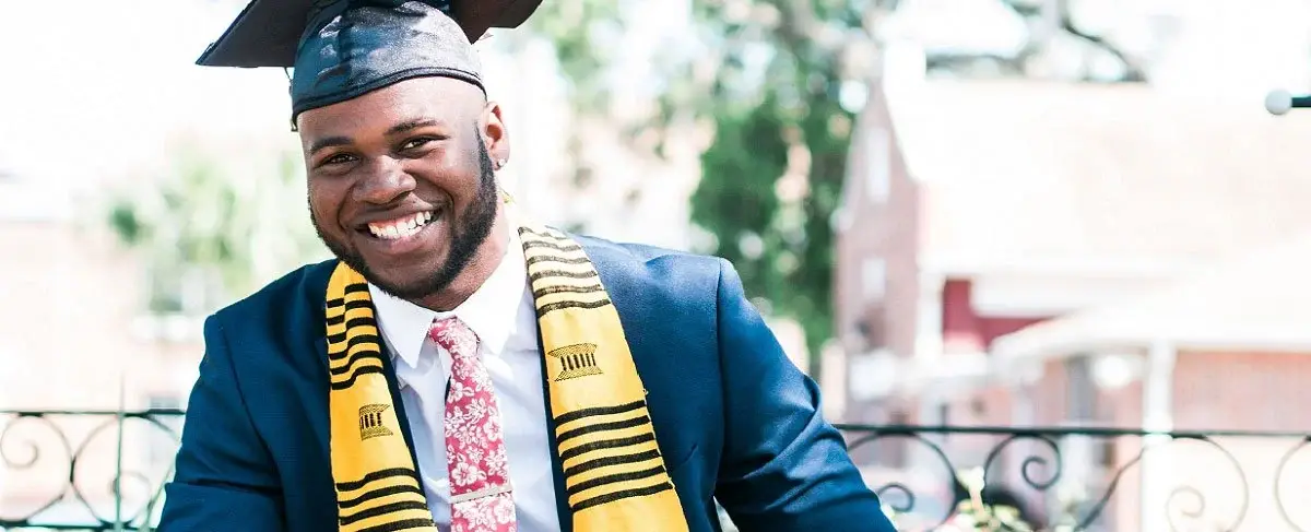 Smiling graduate wearing a cap and a kente stole